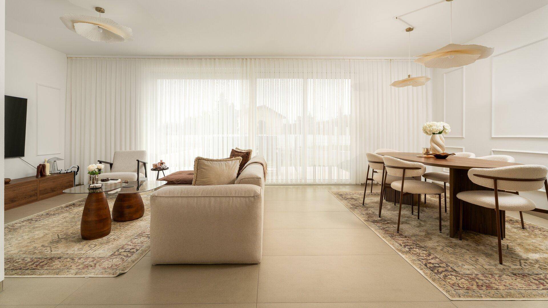 Helles, modernes Wohn-Esszimmer mit großen Fenstern, beigem Sofa und elegantem Esstisch.