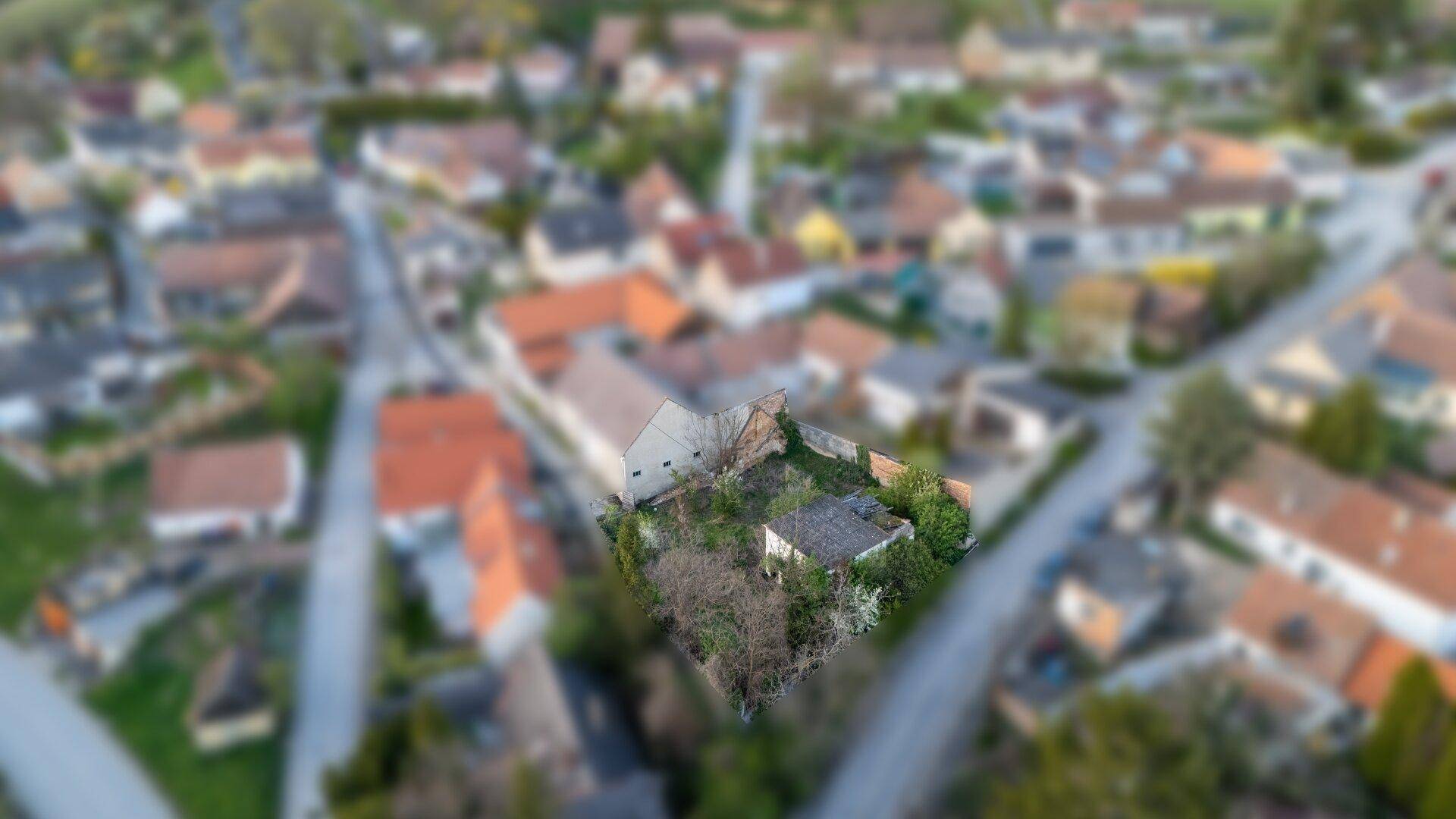 Weitläufige Luftaufnahme des Grundstücks mit baufälligem Gebäude, eingebettet in eine ländliche Wohnsiedlung.