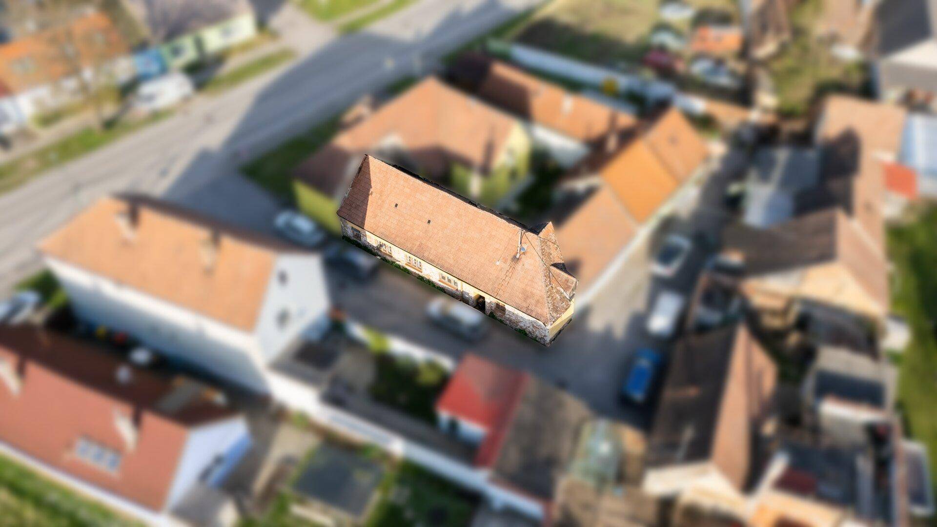 Luftaufnahme eines Wohnhauses mit Ziegeldach in einer ländlichen Umgebung mit weiteren Gebäuden.