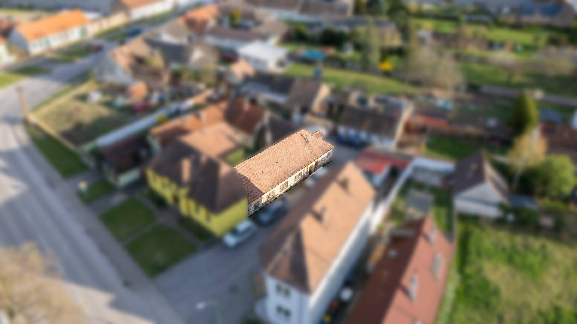 Weitläufige Luftaufnahme eines Wohnhauses mit umliegenden Gebäuden und Gärten in einer Siedlung.