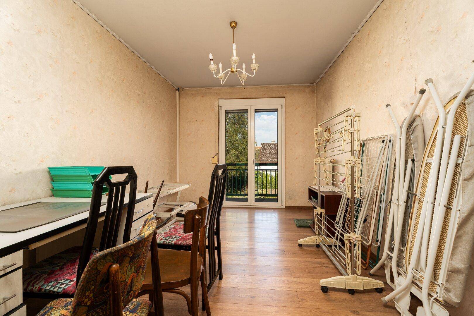 Zimmer mit Holzboden, französischem Balkon und verschiedenen Haushaltsgegenständen.