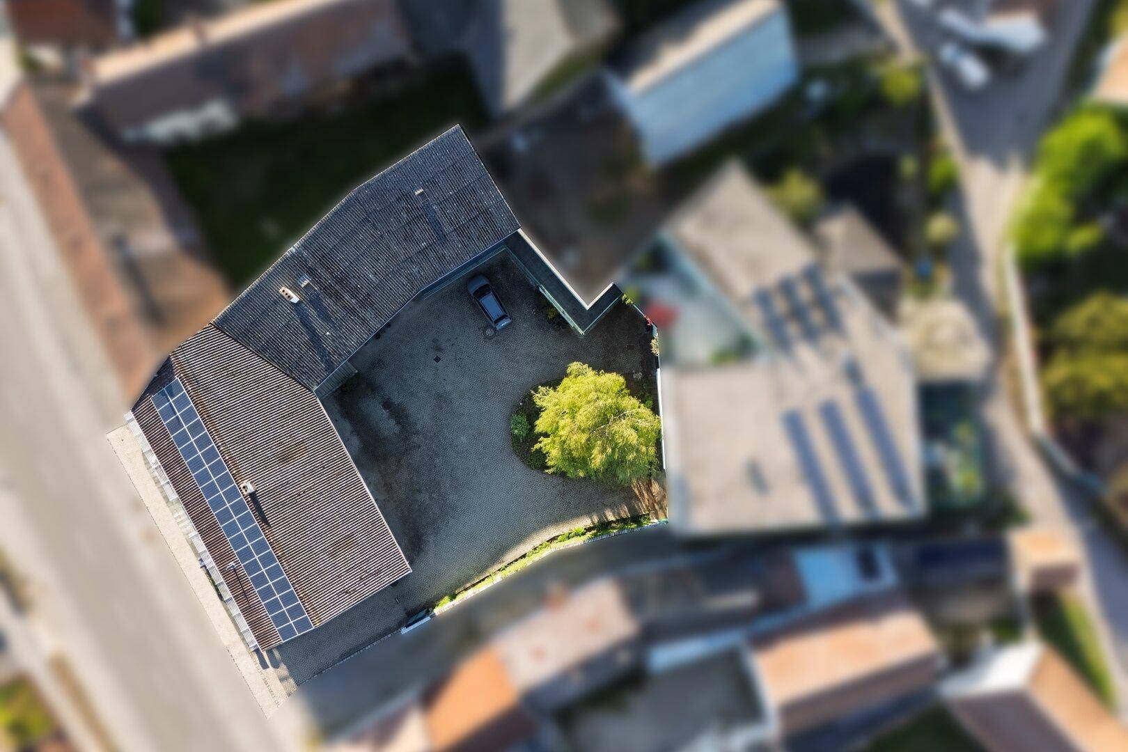 Luftaufnahme des Anwesens mit Solaranlage auf dem Dach und einem Baum im Innenhof.