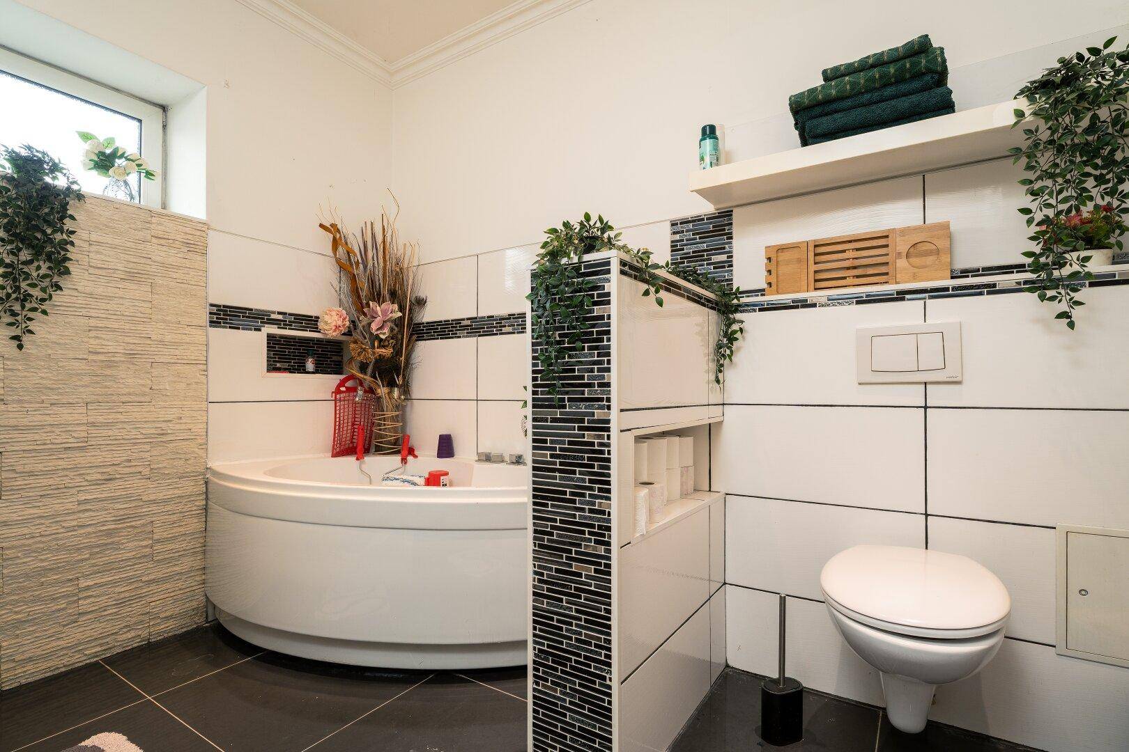Ein modernes Badezimmer mit einer Eckbadewanne, einer wandhängenden Toilette und dekorativen Fliesen.