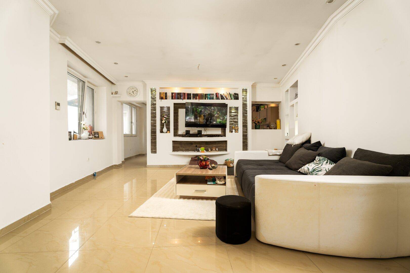 Helles Wohnzimmer mit großer Eckcouch, Couchtisch und einer Medienwand mit integrierten Bücherregalen.