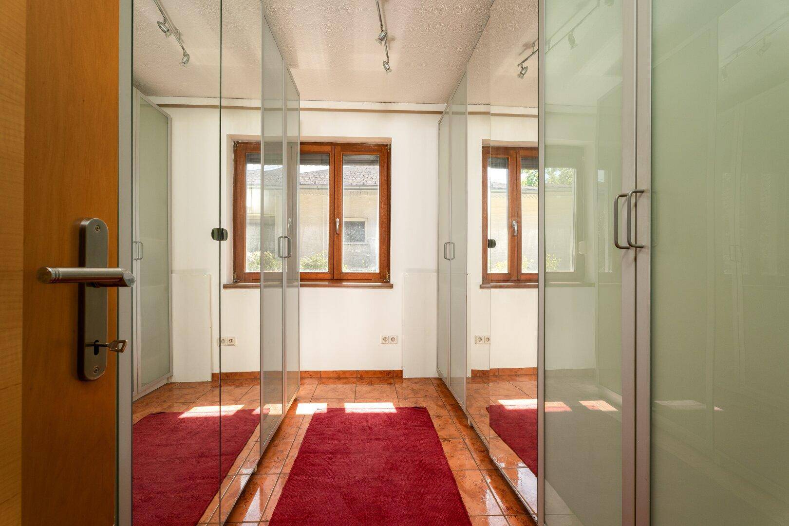Raum mit durchgehenden Spiegelschränken und Terrakotta-Fliesenboden, ideal als Ankleidezimmer.