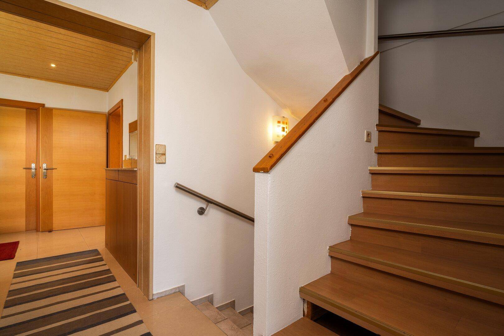 Gemütlicher Flur mit Holztreppe, Holztüren und einer Holzdecke im Landhausstil.