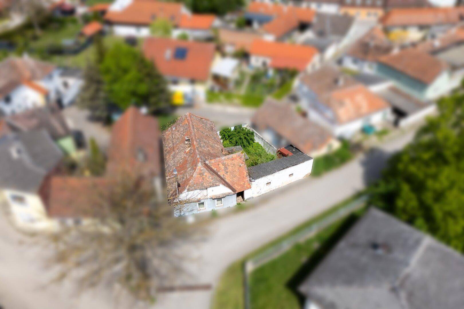 Übersicht aus der Luft, die das Haus mit seinem Grundstück und die umliegende ländliche Bebauung zeigt.