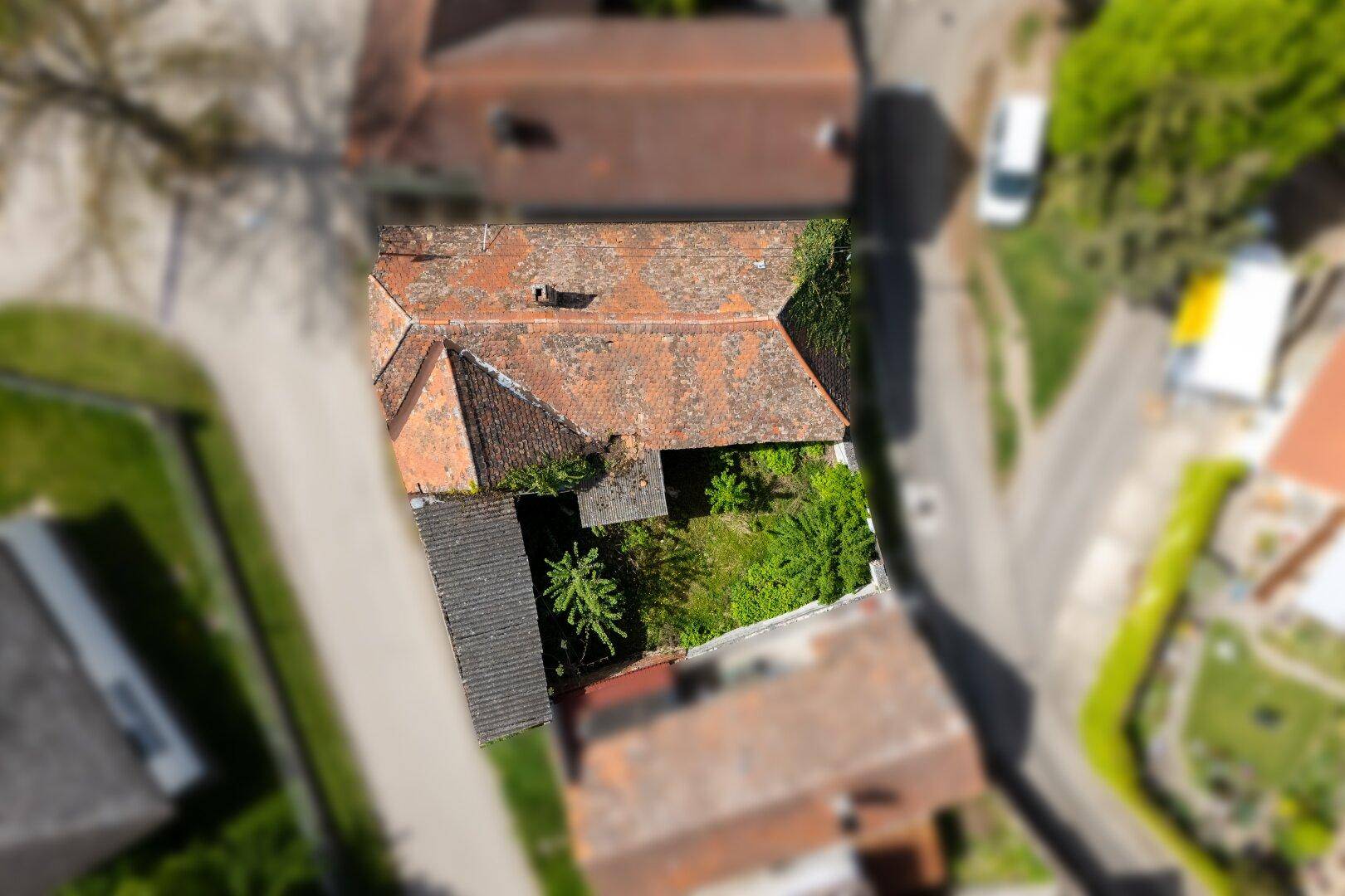 Luftaufnahme des Anwesens mit Ziegeldach und einem kleinen, bewachsenen Innenhof oder Gartenbereich.