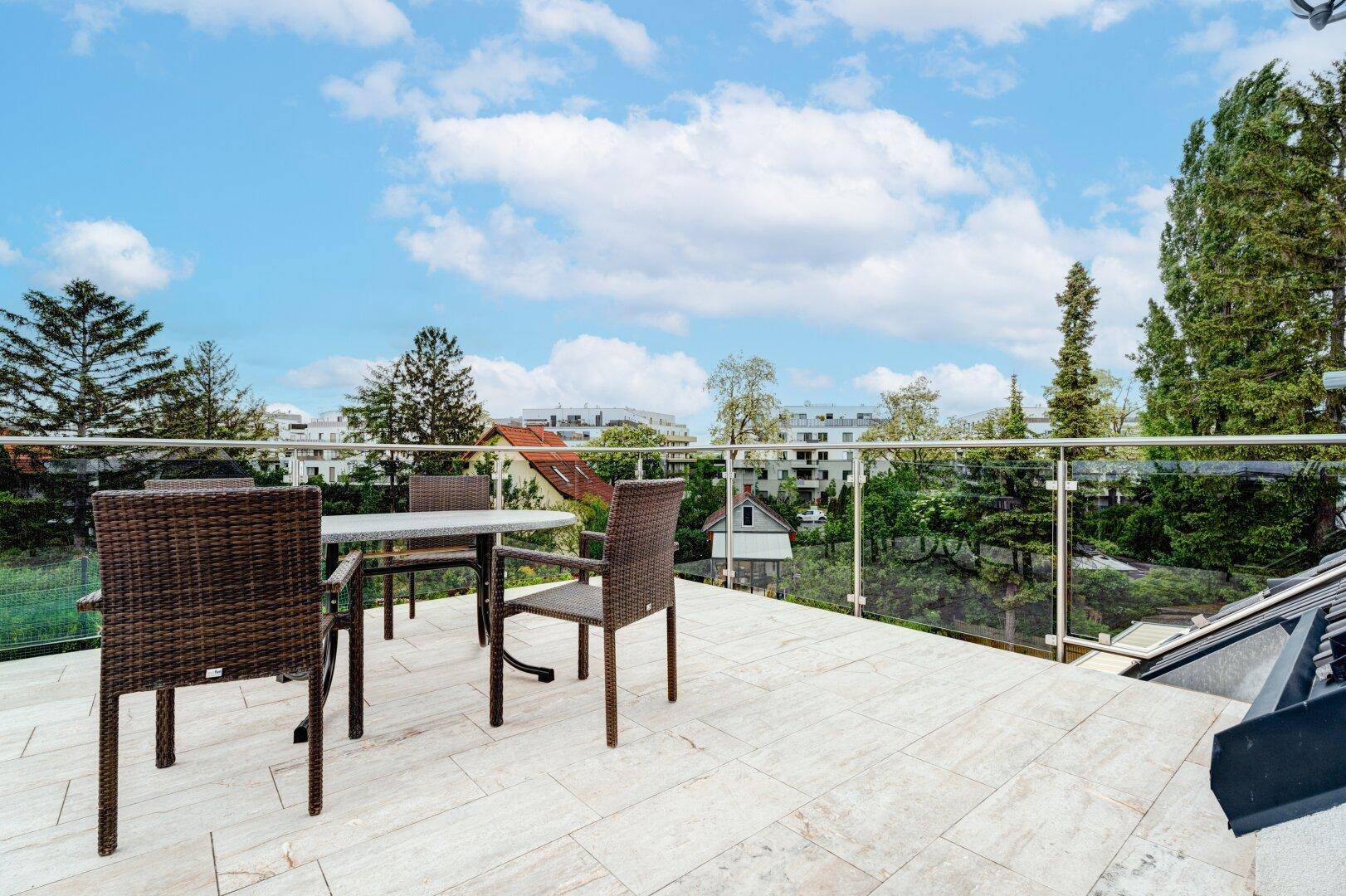 Geräumige Dachterrasse mit Rattanmöbeln und weitem Blick über die Umgebung.