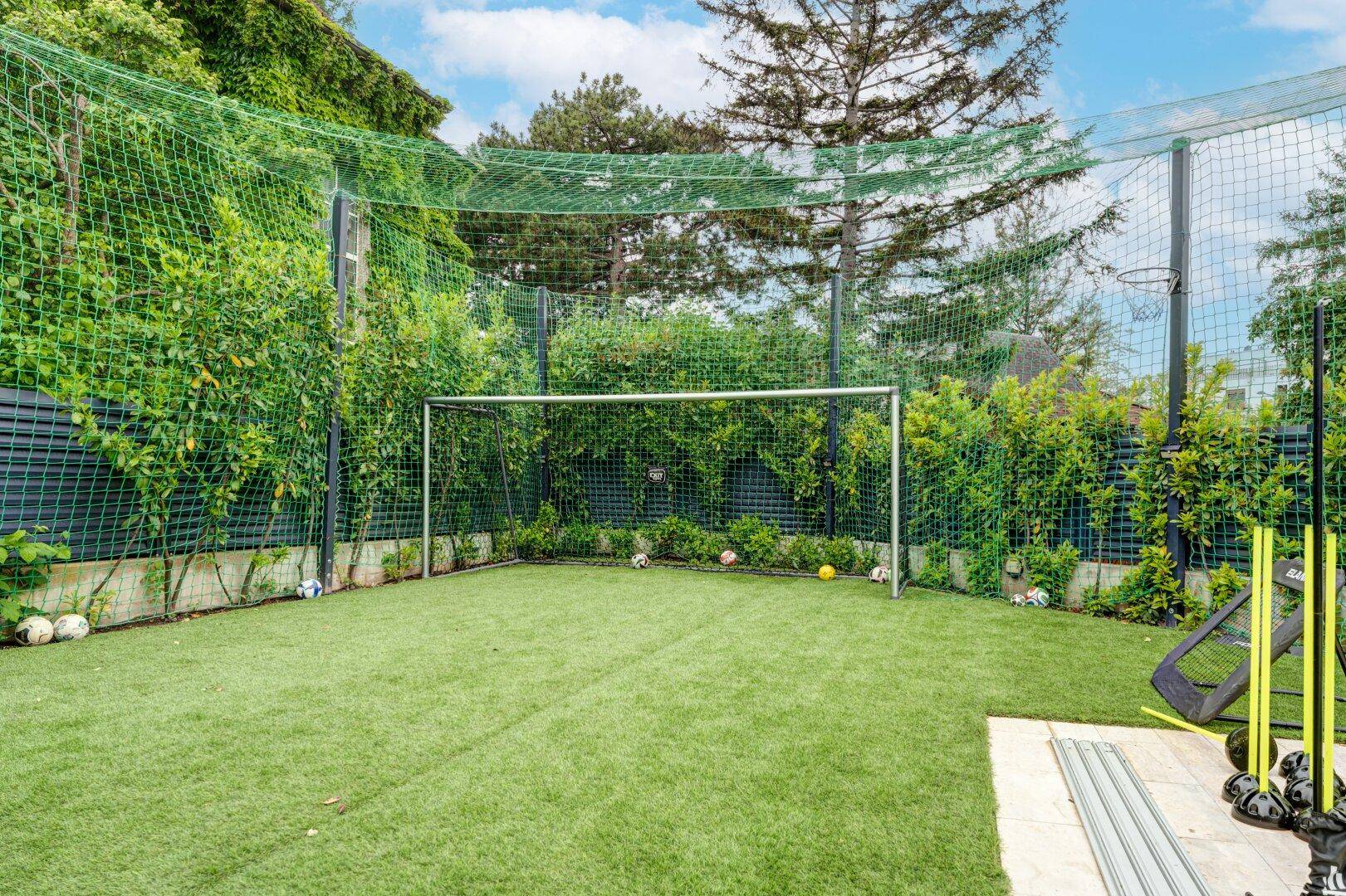 Eigener Sportbereich im Garten mit Fußballtor und schützenden Netzen für Ballspiele.