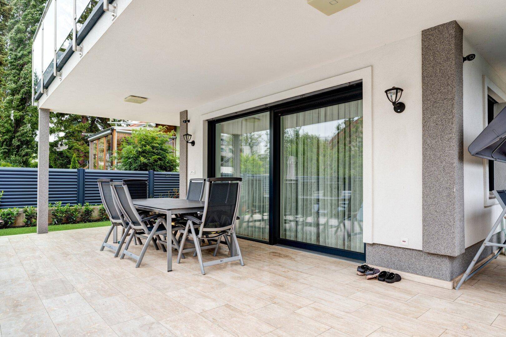Überdachte Terrasse mit Esstisch und Stühlen, ideal für Mahlzeiten im Freien.