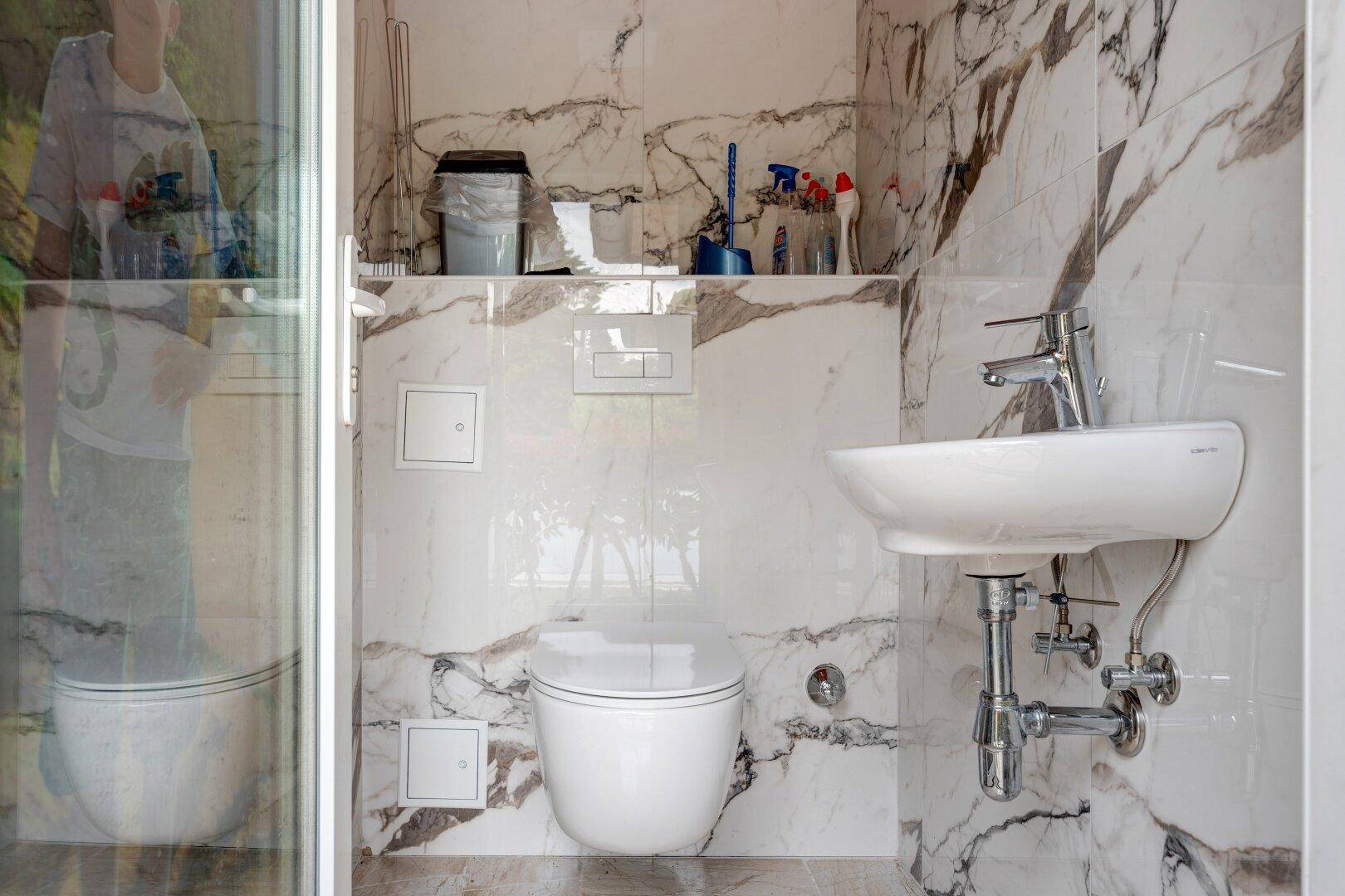 Stilvolles Gäste-WC mit Marmorfliesen, wandhängendem WC und modernem Waschbecken.