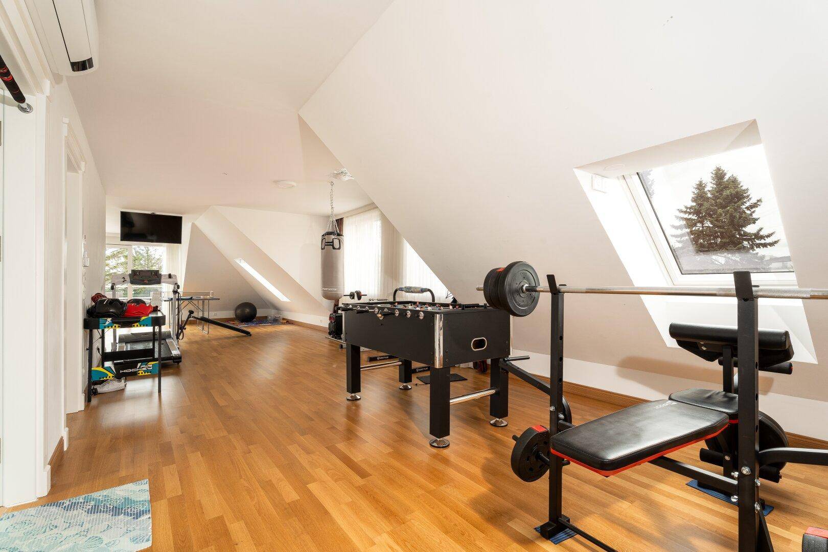 Geräumiger Dachboden als Fitness- und Spielzimmer mit Holzboden und Dachfenstern.