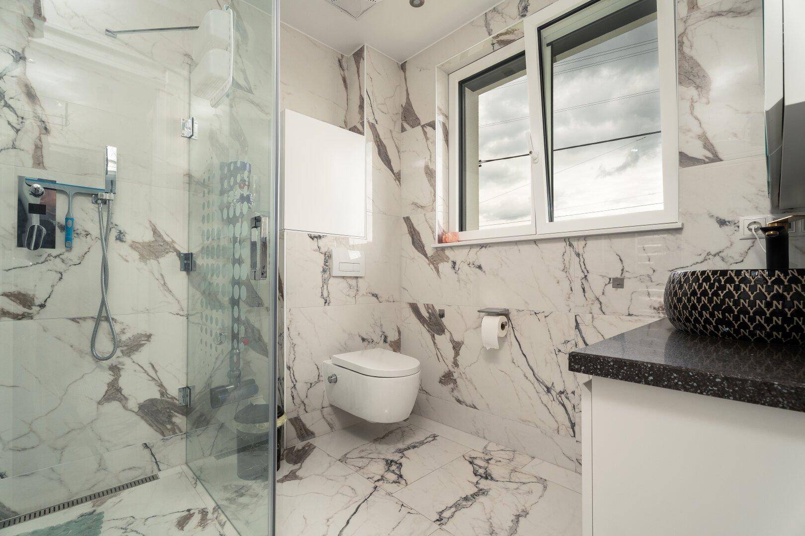 Modernes Badezimmer mit begehbarer Dusche, wandhängendem WC und Marmorfliesen.