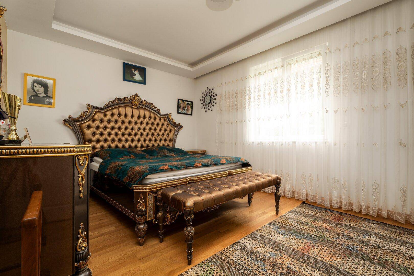 Elegantes Schlafzimmer mit einem opulenten Bett, Holzfußboden und viel natürlichem Licht durch das Fenster.