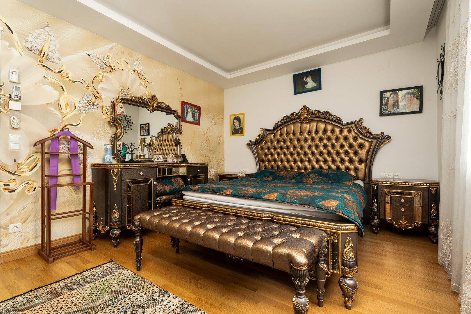 Prunkvolles Schlafzimmer mit einem großen Bett, passender Kommode und einer kunstvoll gestalteten Wand.