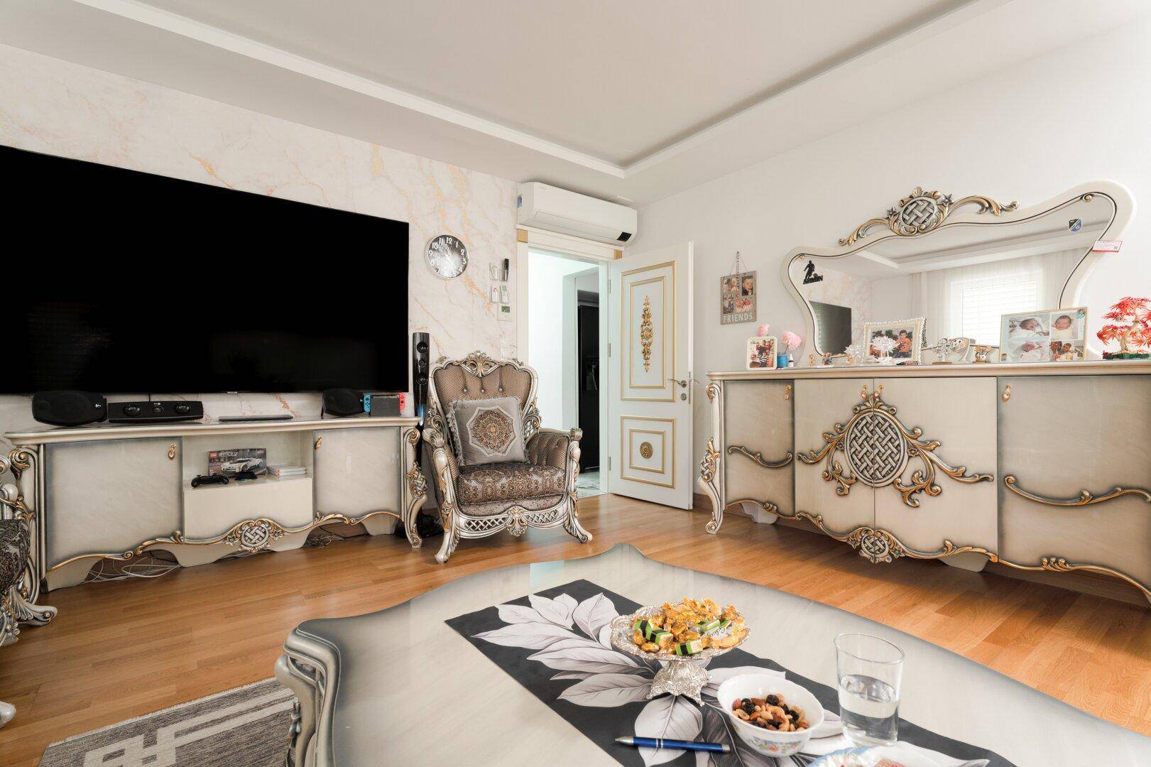 Geräumiges Wohnzimmer mit einem prunkvollen Sideboard, Spiegel und Klimaanlage für angenehmes Raumklima.