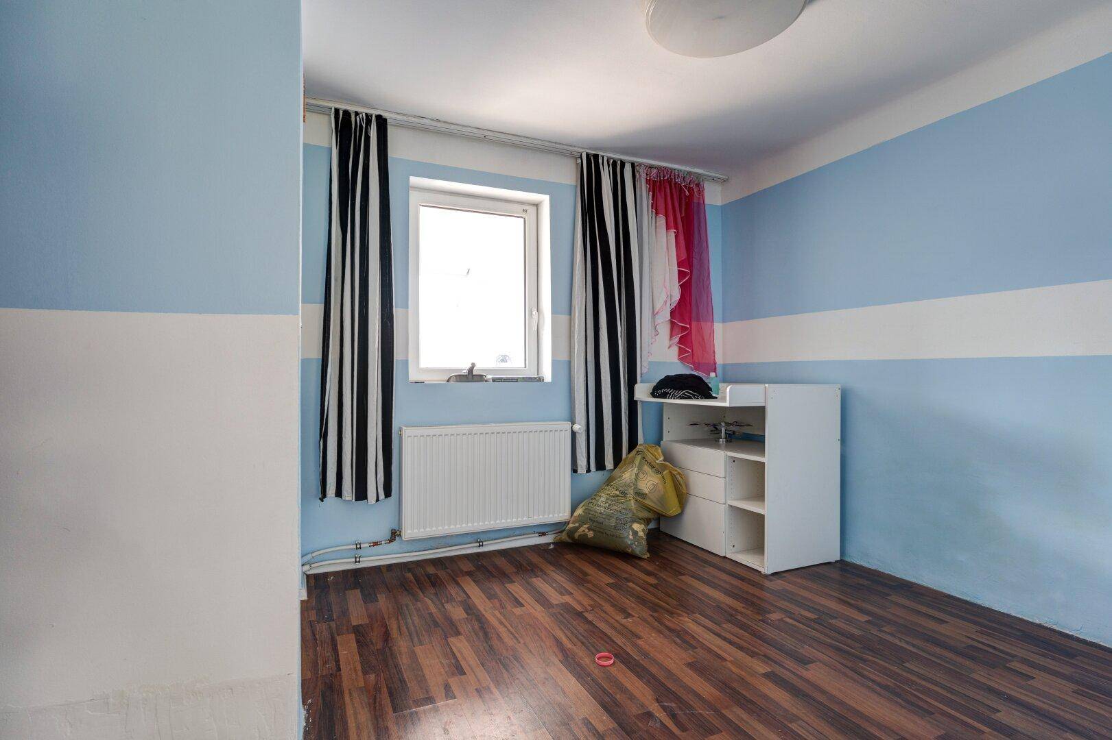 Helles Kinderzimmer mit blau-weiß gestreiften Wänden und Fenster.