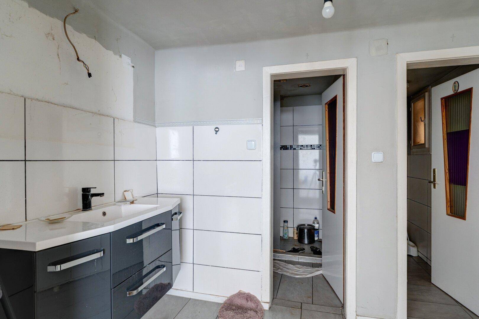 Badezimmer mit modernem Waschtisch, weißen Fliesen und Duschkabine.