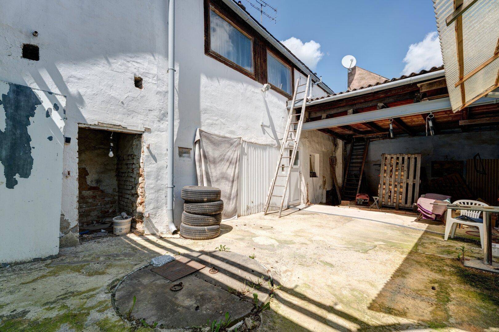 Geräumiger Hinterhof mit Betonboden und Zugang zu Nebengebäuden.
