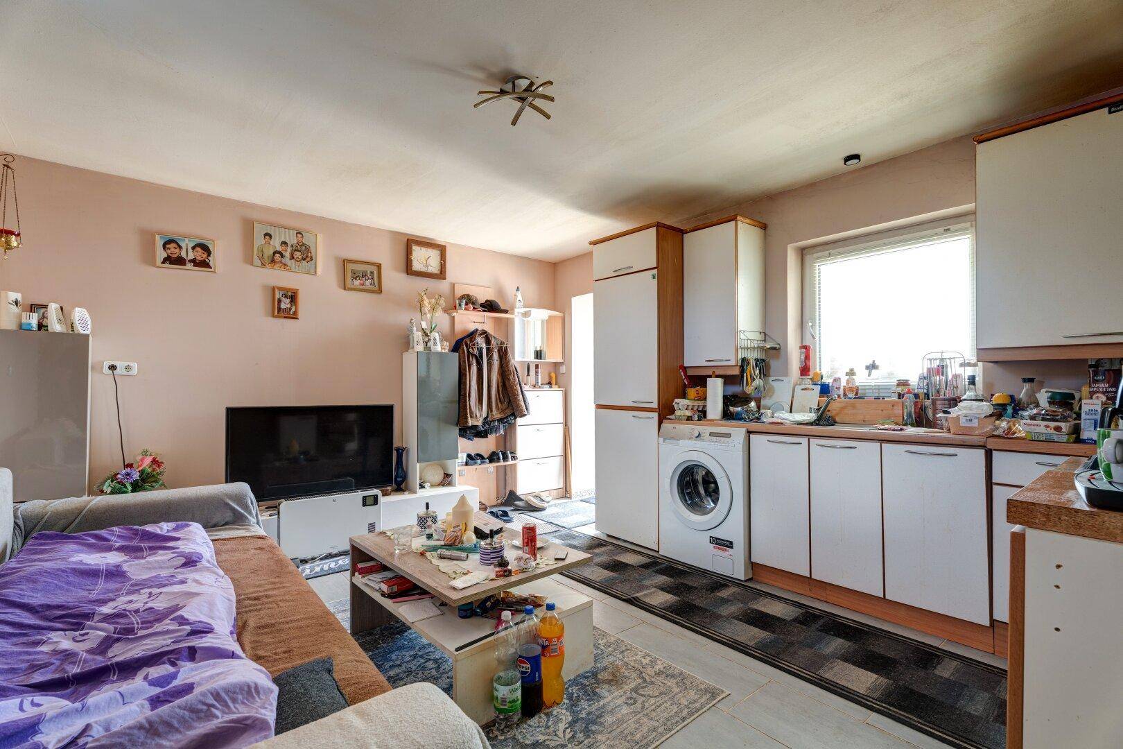 Offener Wohnbereich mit integrierter Küche, Sofa und Fernseher.