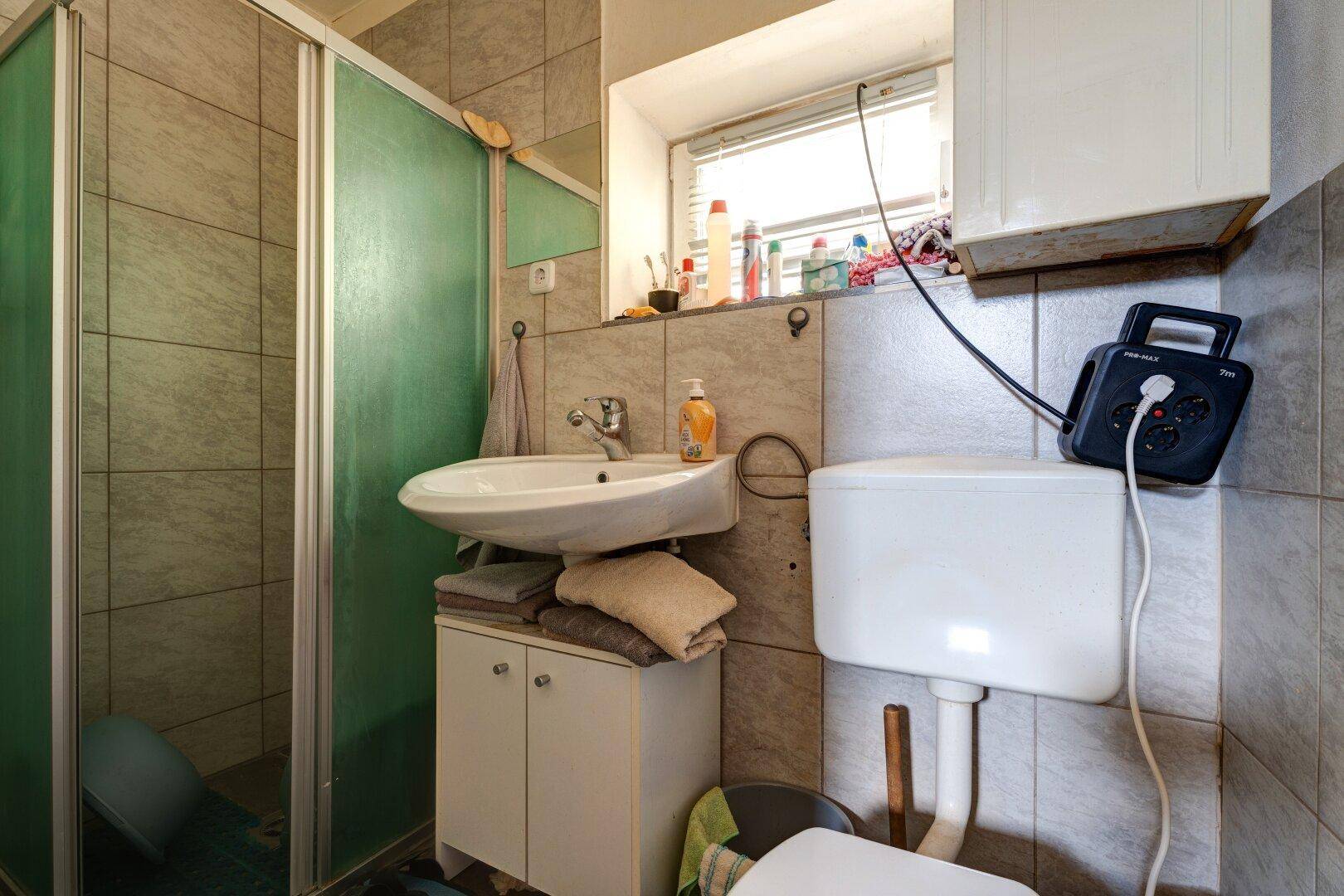 Kleines Badezimmer mit Dusche, WC und Waschbecken.