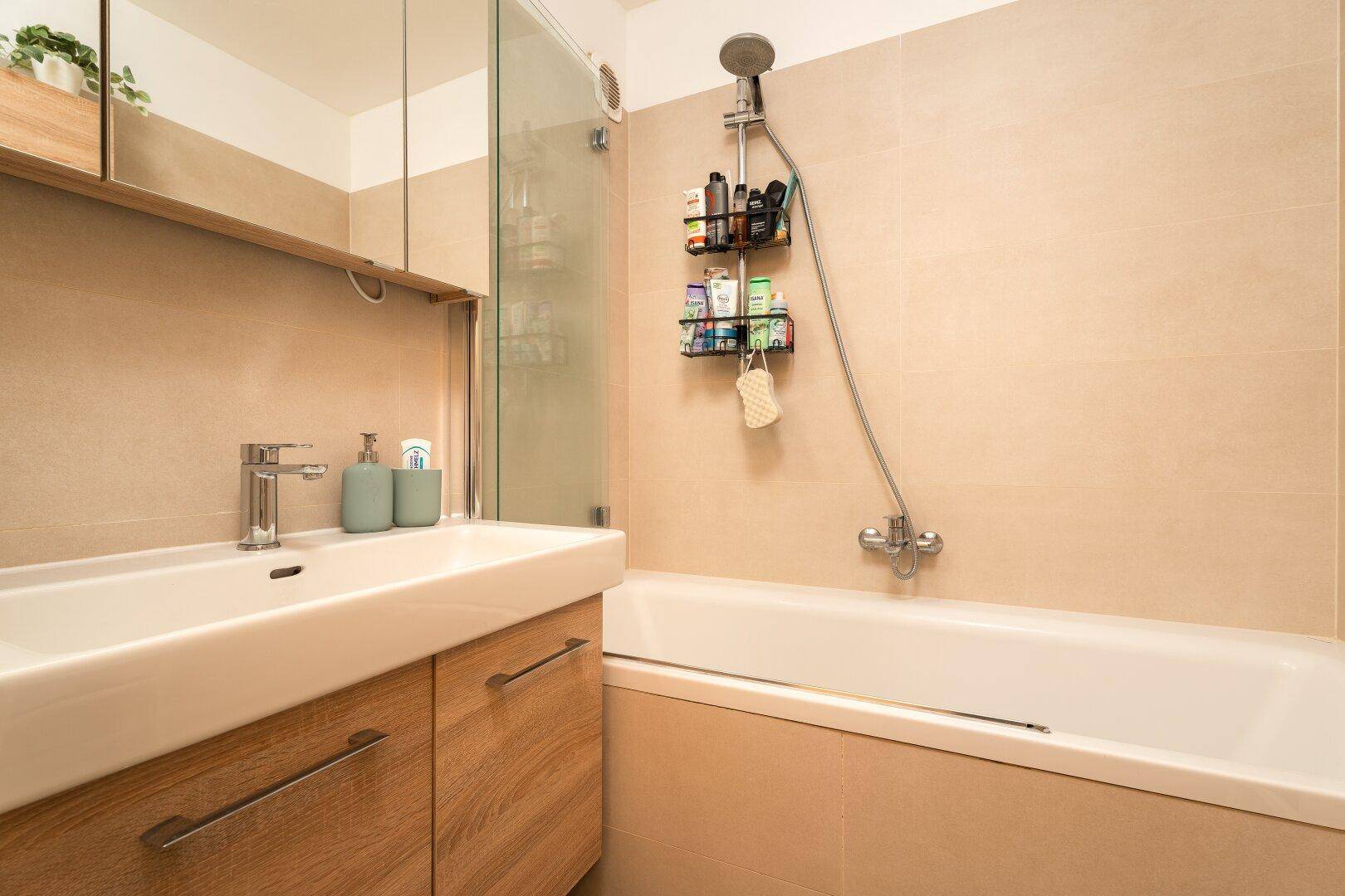 Helles Badezimmer mit Badewanne, Duschfunktion und modernem Waschtisch.