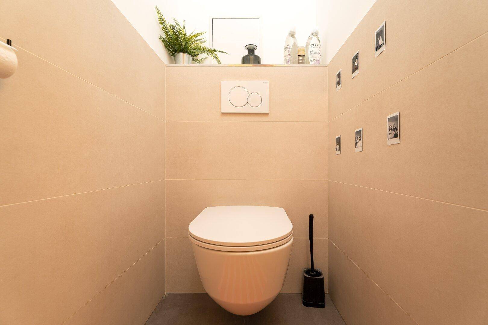 Modernes Gäste-WC mit wandhängender Toilette und beigefarbenen Fliesen.