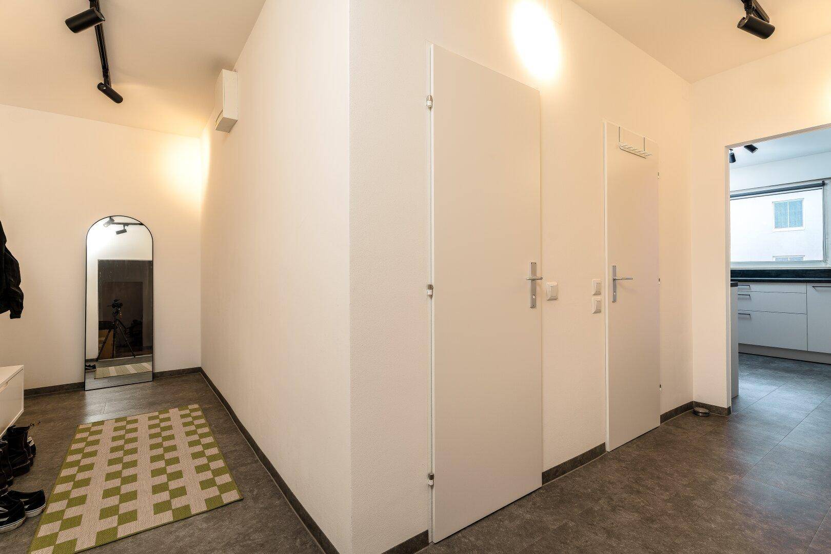 Heller Flur mit modernem Spiegel, Garderobe und Fliesenboden.
