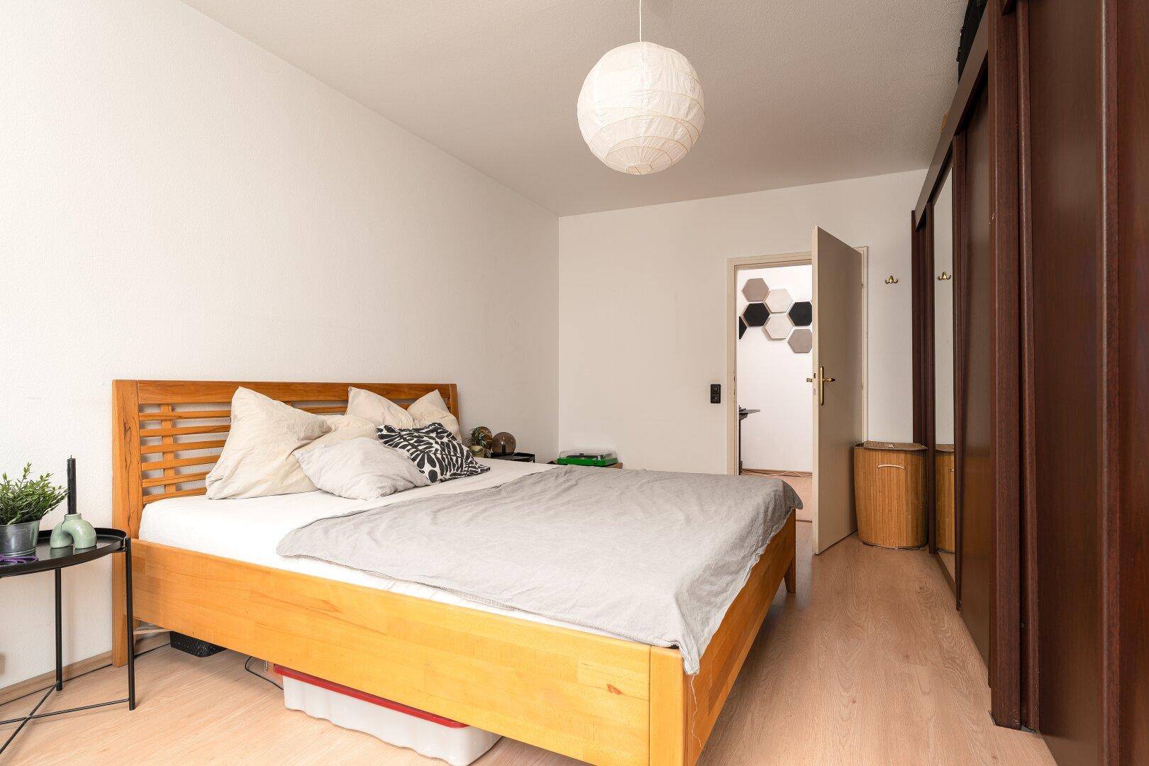 Gemütliches Schlafzimmer mit Holzbett, großem Kleiderschrank und Zugang zu einem weiteren Raum.