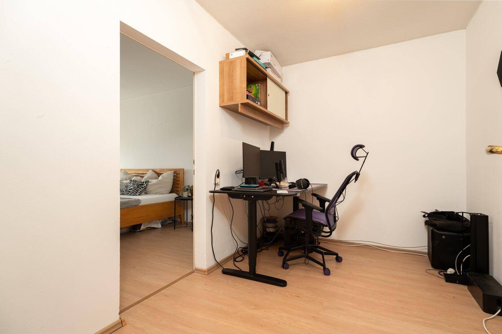 Kleiner Arbeitsbereich mit Schreibtisch und Blick in ein angrenzendes Schlafzimmer.