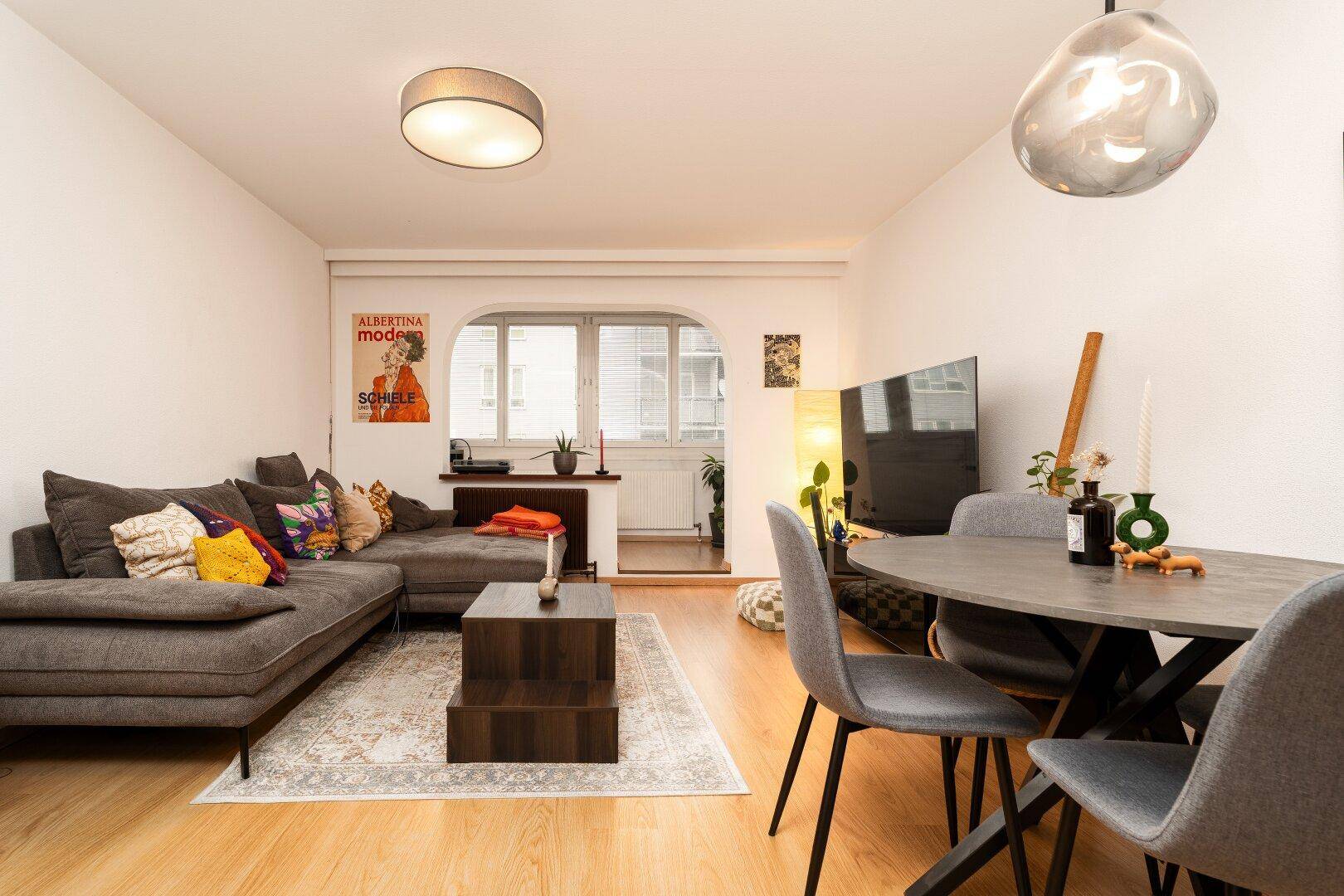 Geräumiger Wohn- und Essbereich mit bequemer Couch, Esstisch und hellem Parkettboden.