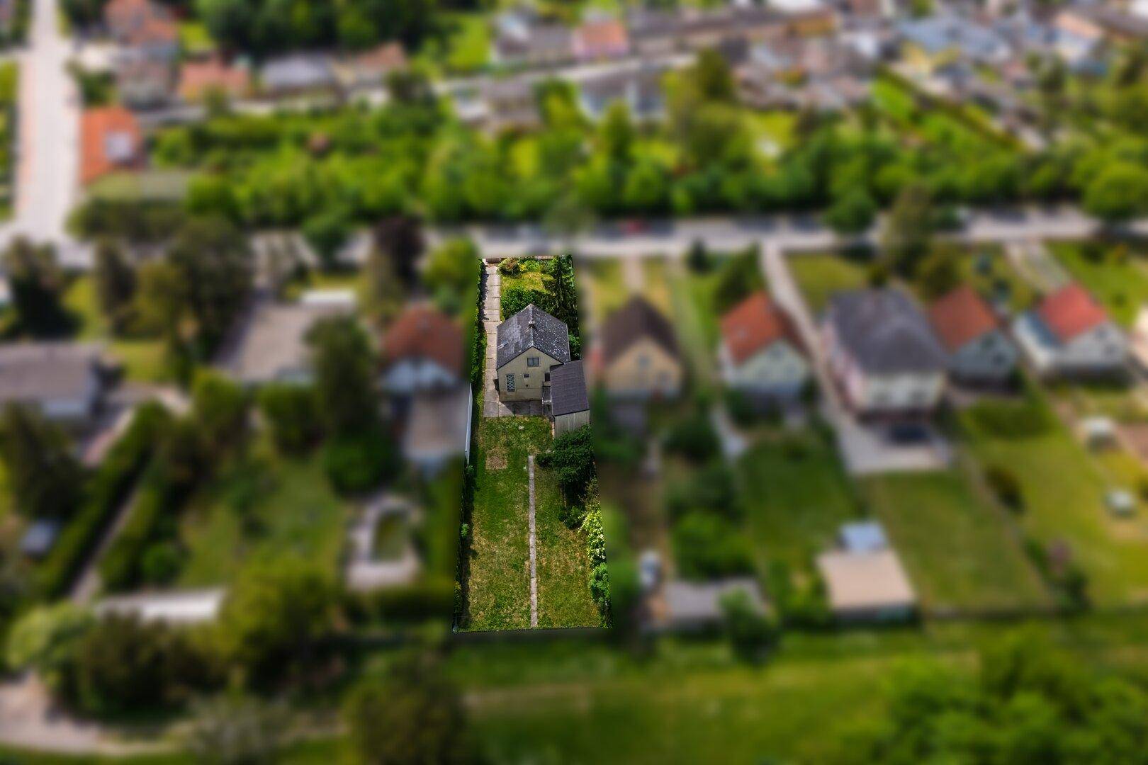 Übersicht aus der Luft eines Hauses mit großem Garten, eingebettet in eine grüne Wohnsiedlung.