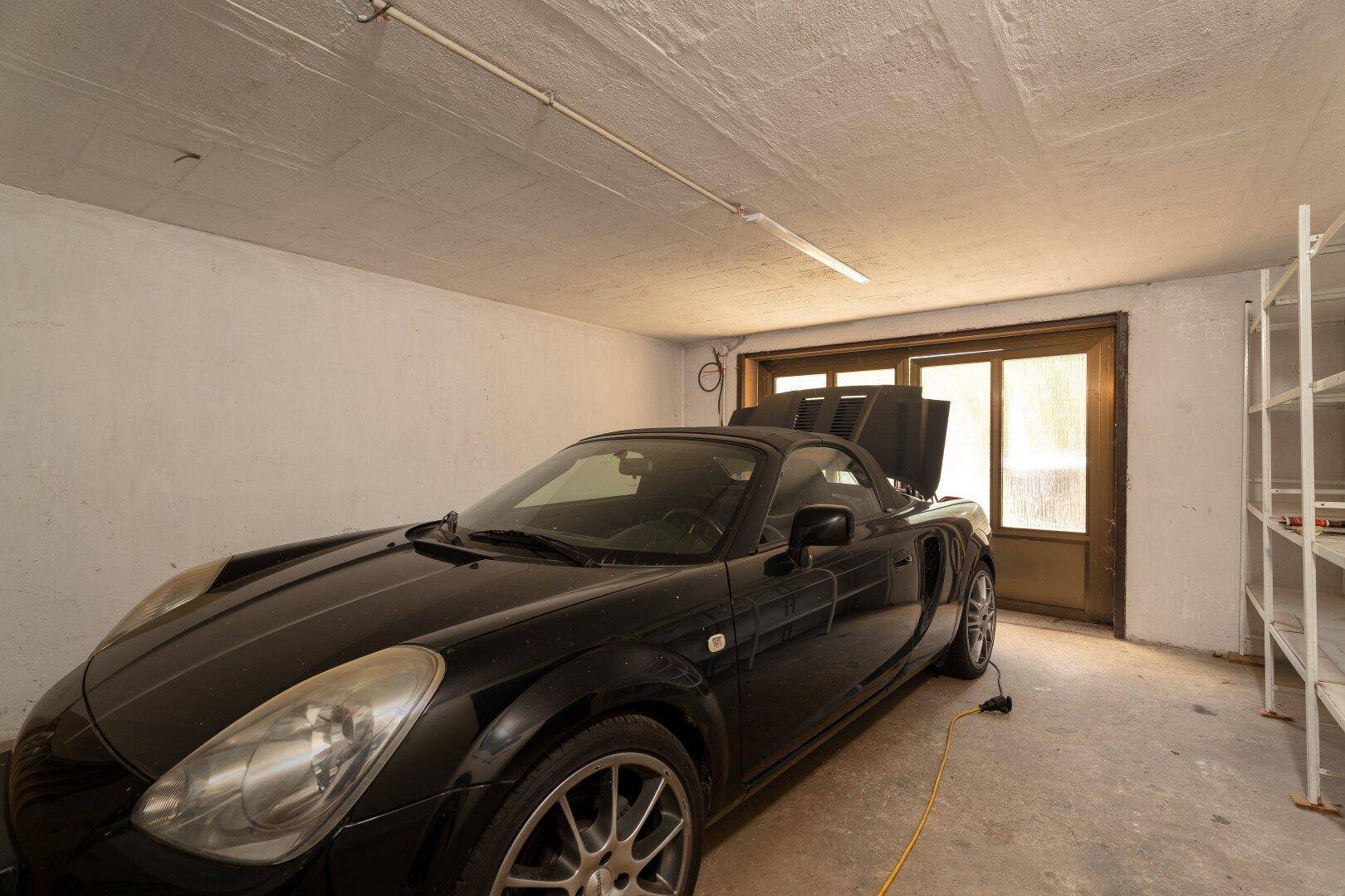 Geräumige Garage mit Betonboden und einem geparkten Sportwagen, ideal für Fahrzeuge und Lagerung.