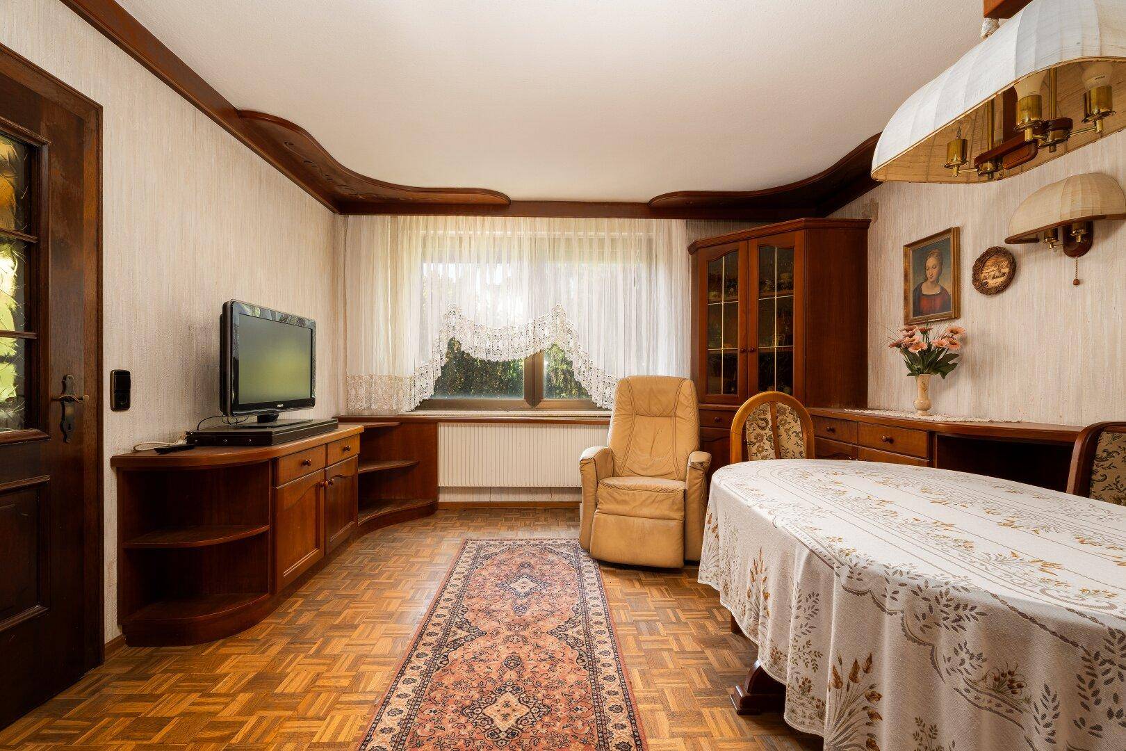 Heller Essbereich mit Holzboden, traditionellen Möbeln und einem Fenster mit Vorhängen.