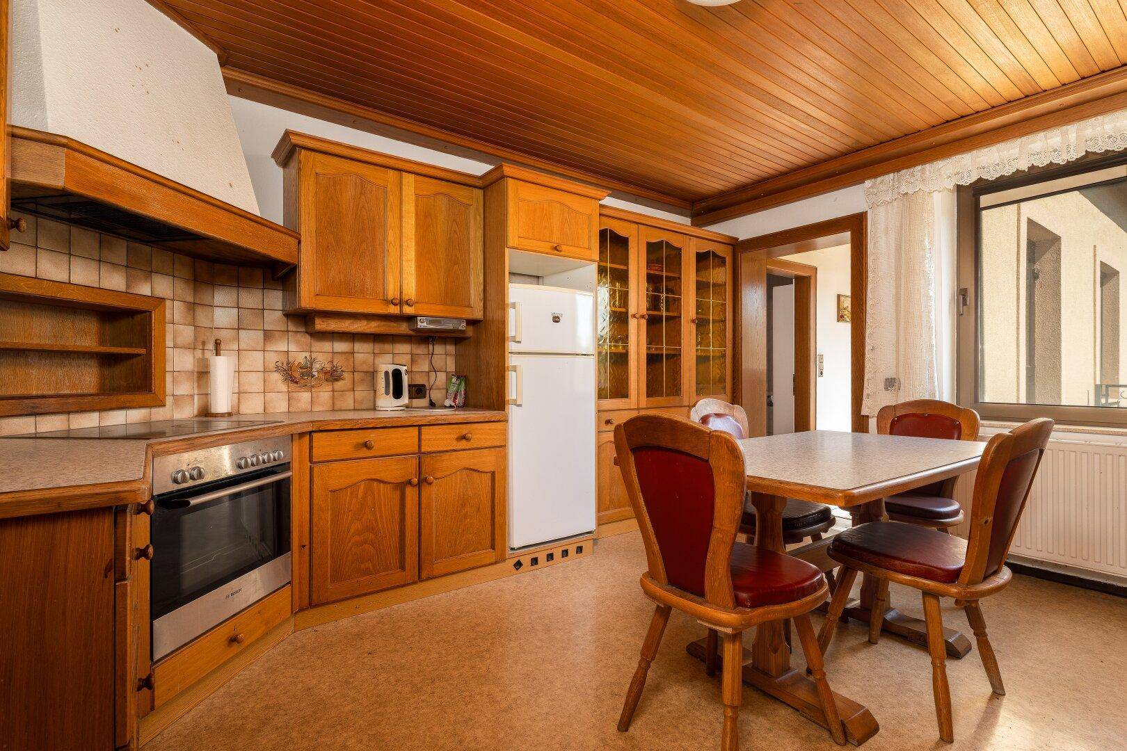 Geräumige Holzküche mit integrierten Geräten, Essbereich und Fenster für natürliches Licht.