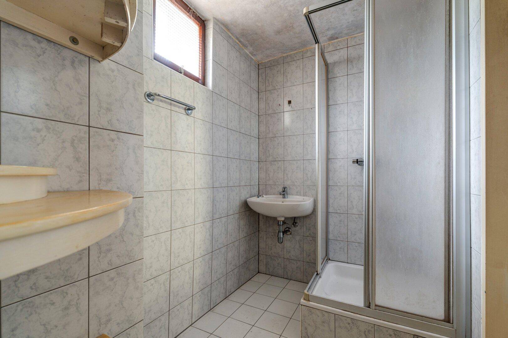 Badezimmer mit Fliesen, Waschbecken und einer Duschkabine.