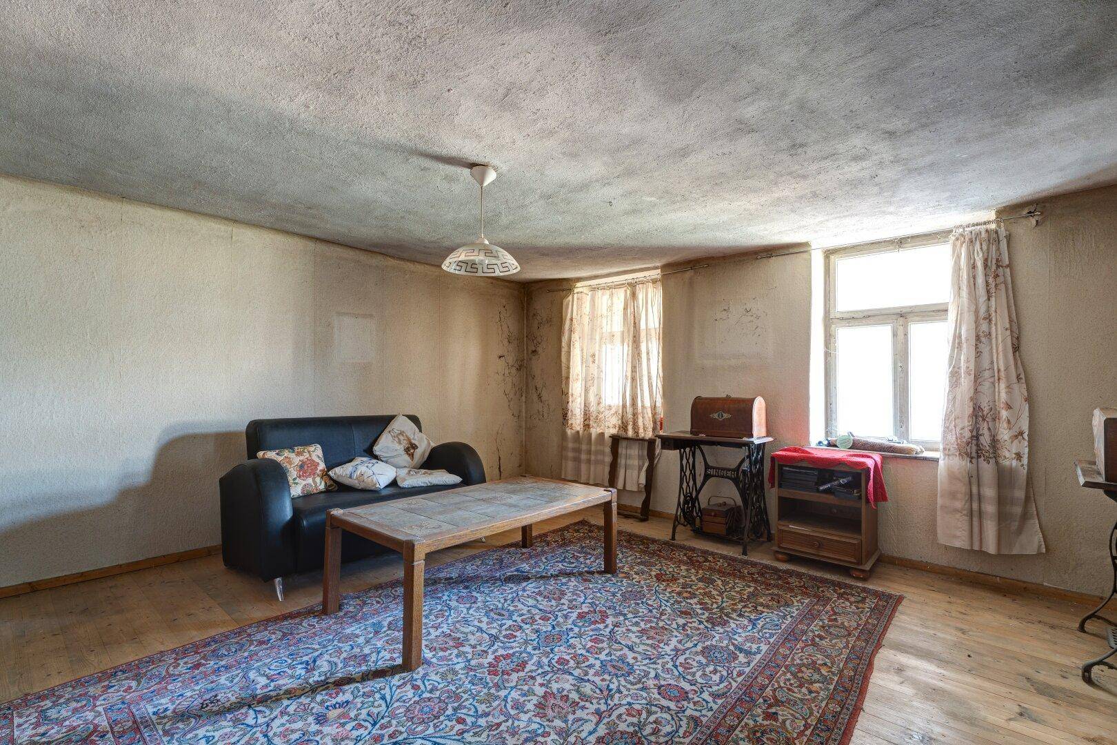 Helles Wohnzimmer mit Holzboden, bequemer Couch und großen Fenstern für viel Tageslicht.
