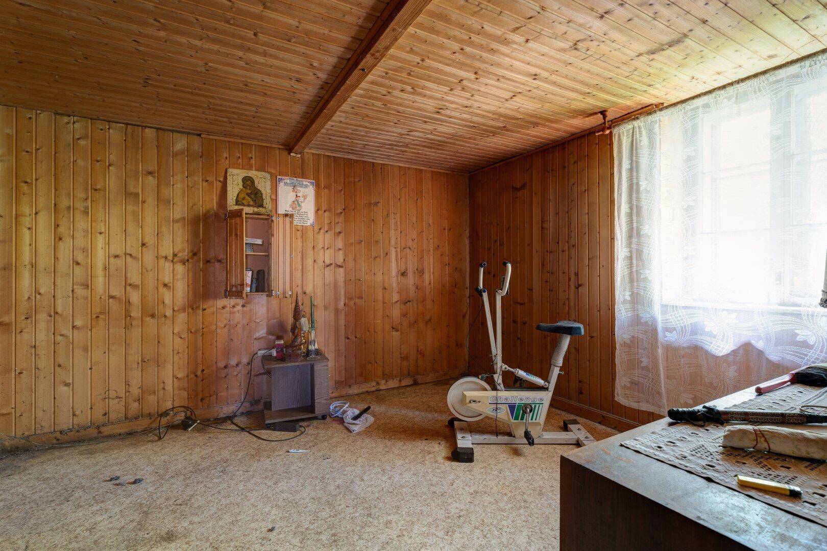 Zimmer mit Holzvertäfelung an Wänden und Decke, ausgestattet mit einem Heimtrainer.