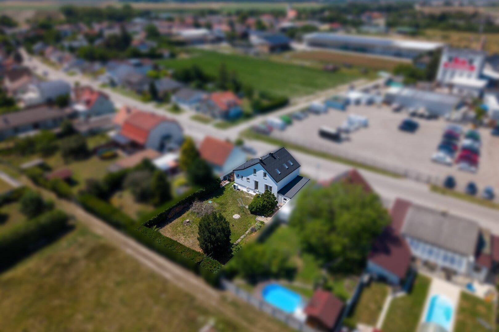 Panoramablick von oben auf ein Wohnhaus mit gepflegtem Garten und angrenzenden Feldern.