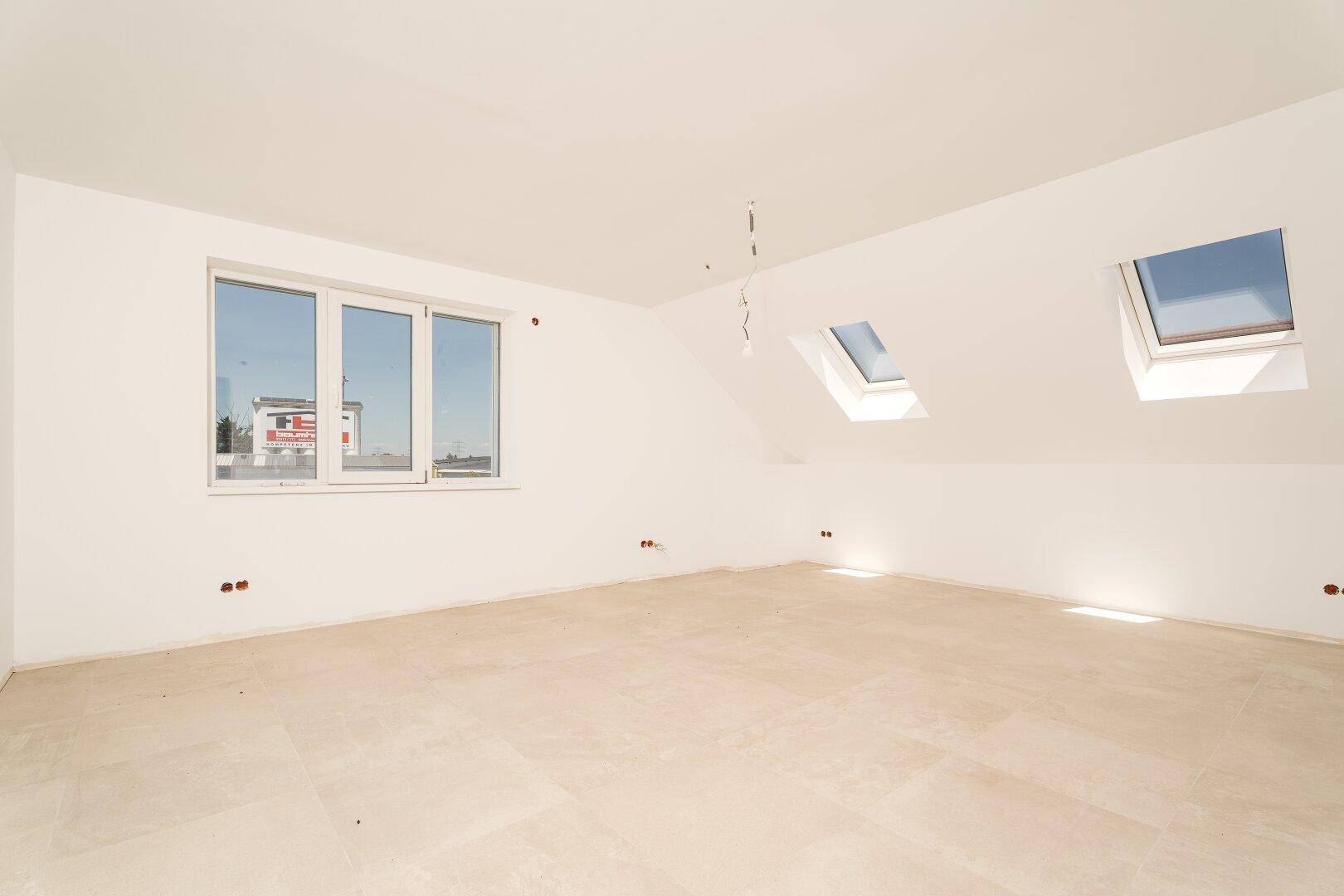 Heller Dachbodenraum mit Fliesenboden, einem Fenster und zwei zusätzlichen Dachfenstern.