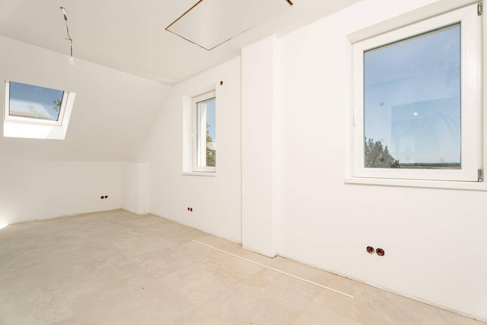Heller Dachbodenraum mit einem Fenster, einem Dachfenster und schrägen Wänden.