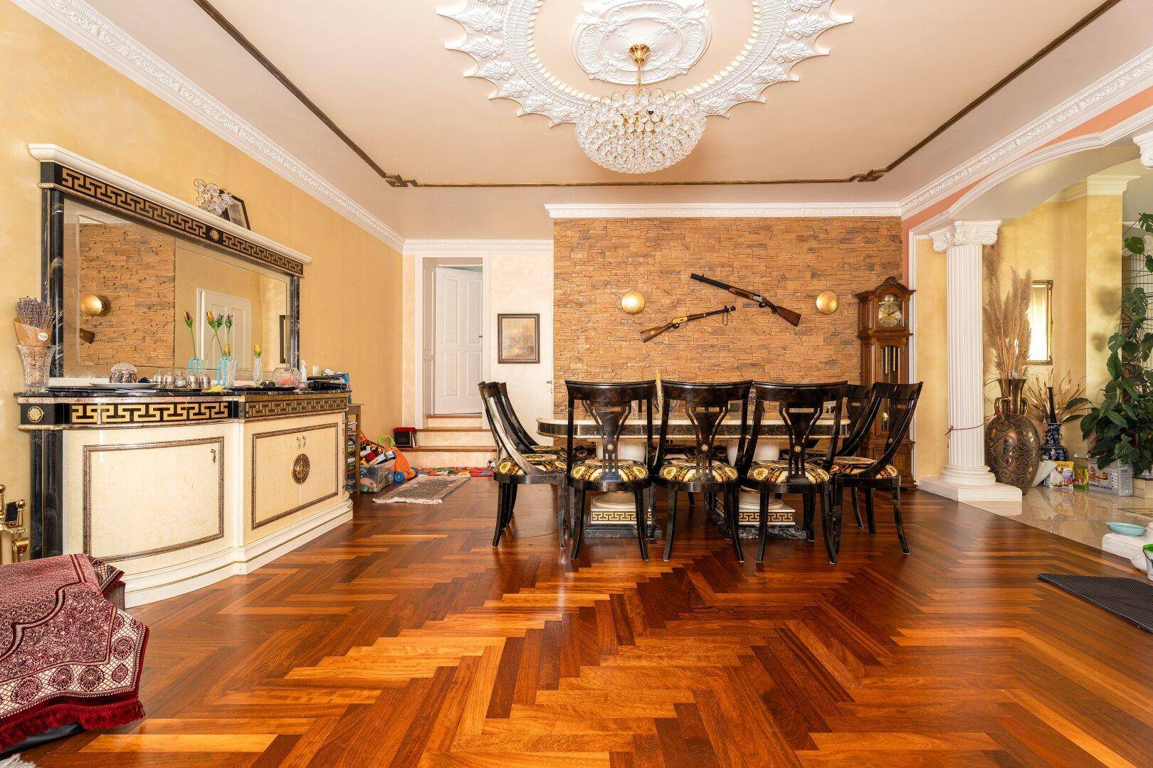 Repräsentativer Essbereich mit großem Holztisch, Fischgrätparkett und dekorativer Steinwand.