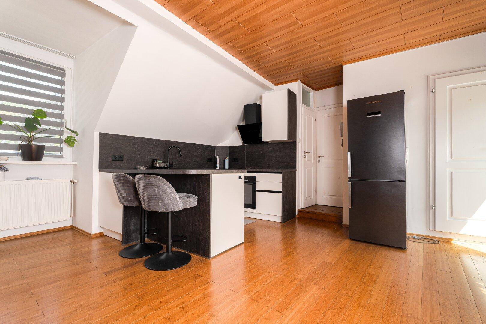 Moderne Küchenzeile im Dachgeschoss mit Frühstücksbar und Holzdeckenverkleidung.
