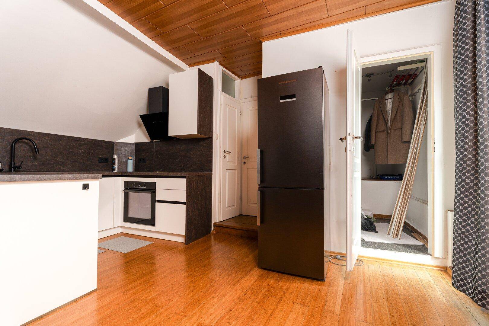 Küchenzeile im Dachgeschoss mit Kühlschrank und integriertem Einbauschrank.