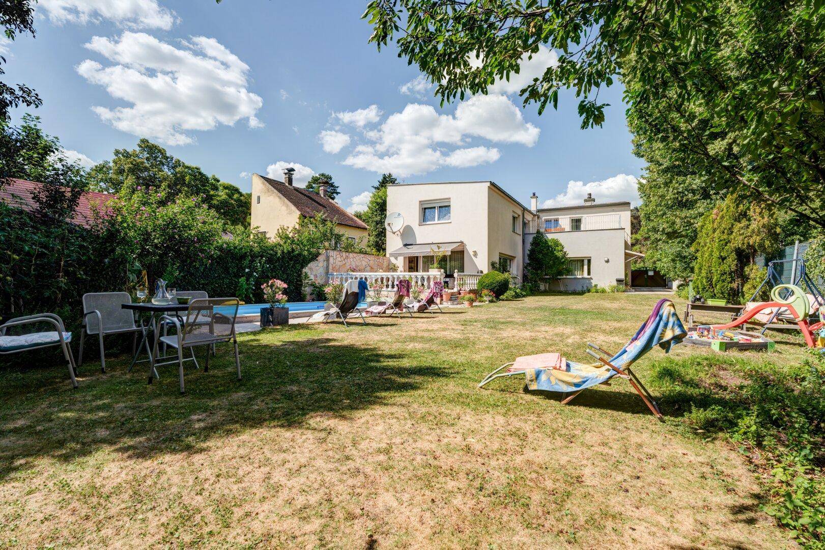 Geräumiger Garten mit Rasenfläche, Swimmingpool und Sitzgelegenheiten im Freien hinter dem Haus.