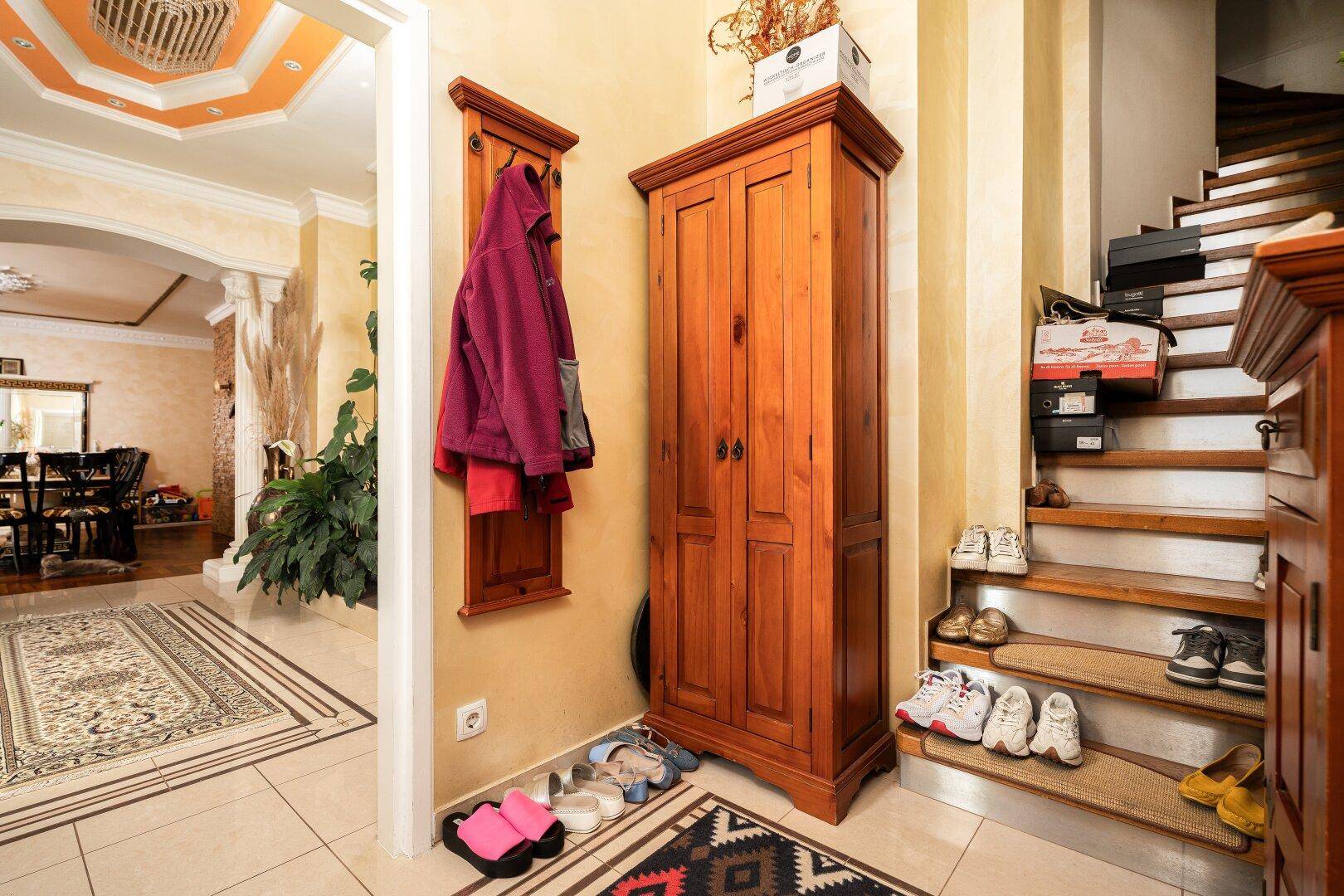 Eingangsbereich mit Holzgarderobe, Schuhregal und Zugang zum Esszimmer.