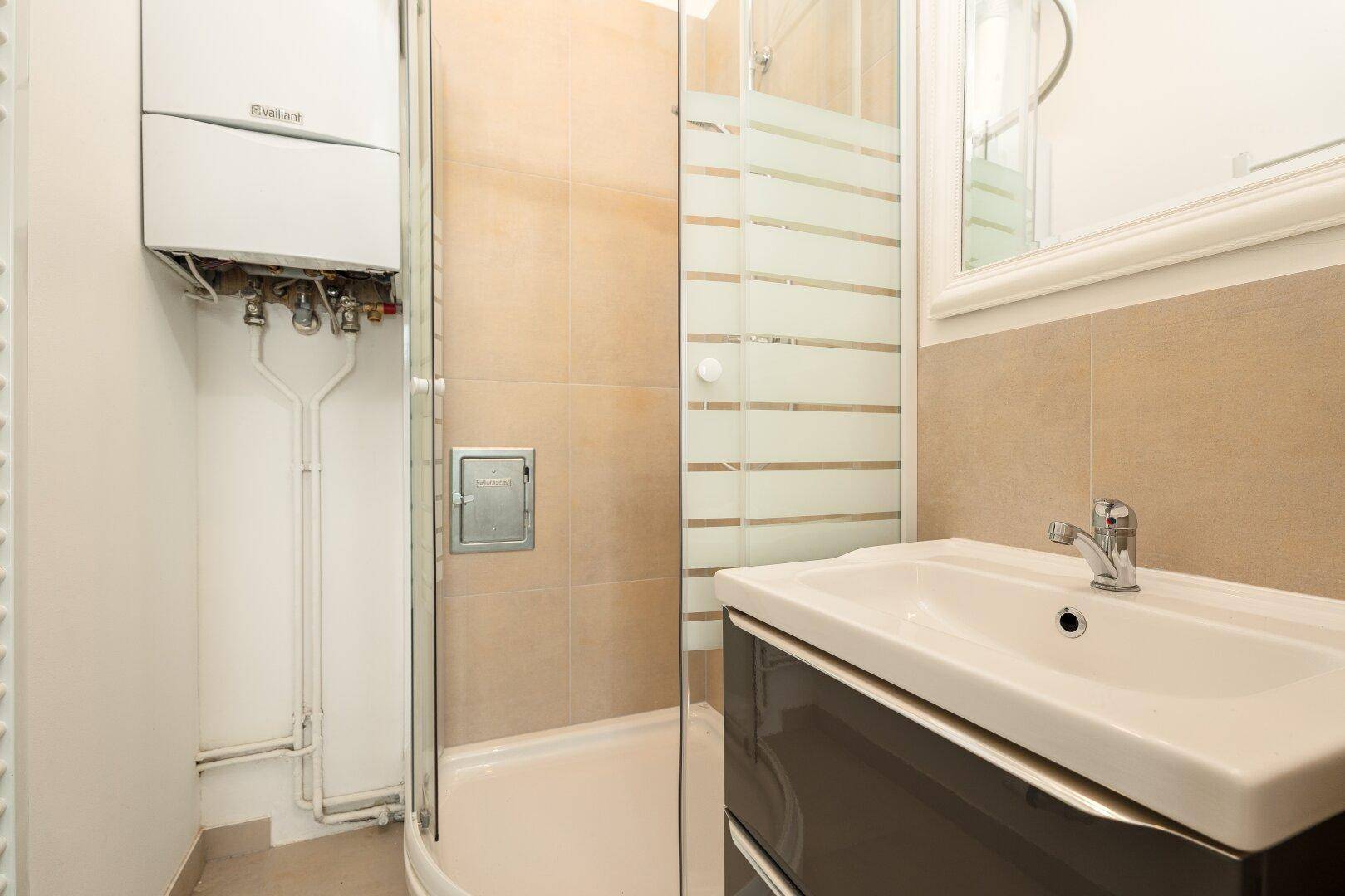 Modernes Badezimmer mit Duschkabine, Waschbecken und Gastherme an der Wand.
