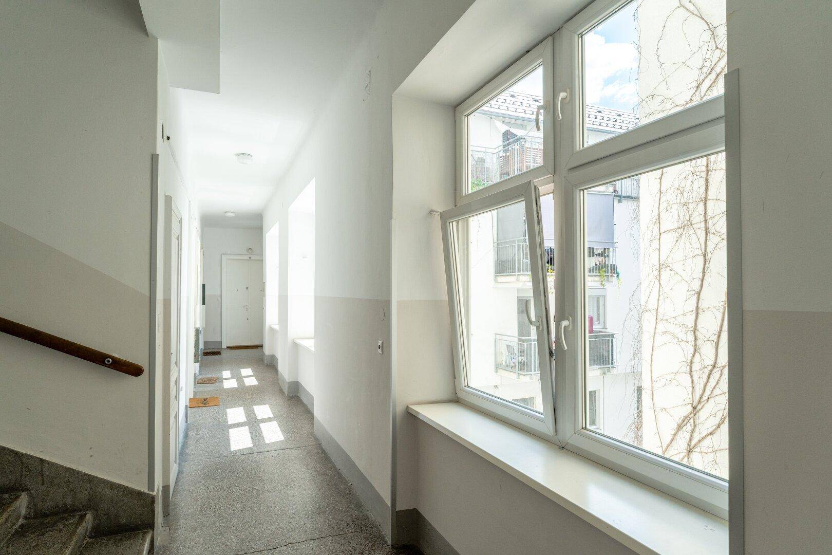 Heller Flur mit Fenstern, die den Blick auf den Innenhof freigeben.