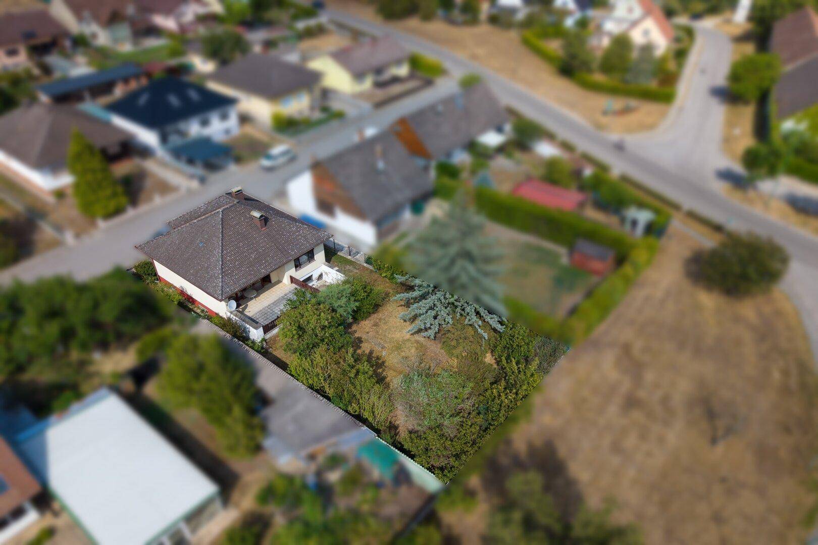Luftaufnahme eines Einfamilienhauses mit großem Grundstück und umliegender Wohnsiedlung.